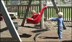 A kid falls out of a swing then gets hit by it