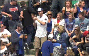 A guy knocks a beer out of someone's hand when he throws a baseball back into the field