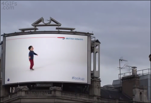 A boy in an airplane advertisement appears to be aware of a real life plane in the sky