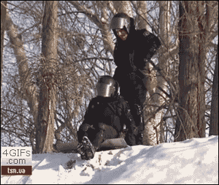 Riot cop uses his shield to sled down a snow hill