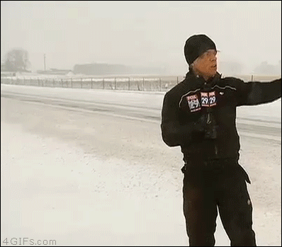 A snow plow knocks down a reporter with a wave of snow and ice being cleared