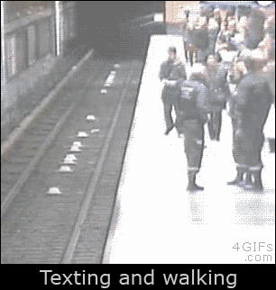A man falls onto train tracks when he is texting instead of looking ahead