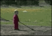 A kid lifts a shovel full of dirt into the air and it spills on his face