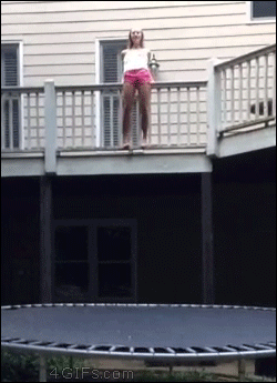 A girl jumps from a deck onto a trampoline