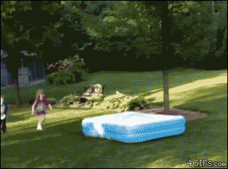 Kids chase after an inflatable pool being moved by a dog