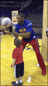 A guy shows a kid a basketball trick and they both celebrate