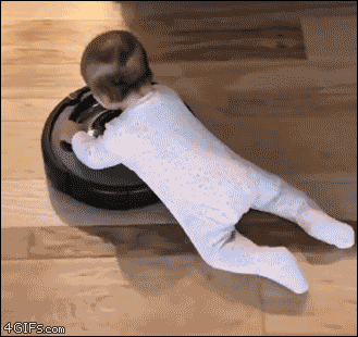 A baby rides a roomba