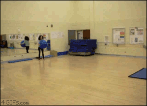 Two girls run at each other with exercise balls
