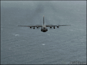 A C-130 military aircraft shoots flares that look like angel wings in the smoke